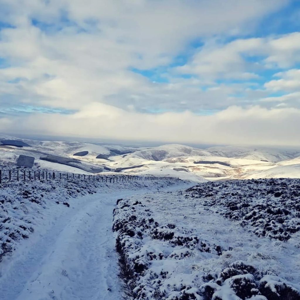 Running the UK’s loneliest Ultra - The Montane Cheviot Goat - a snowy scene from the race of hills and a track dipping away in front