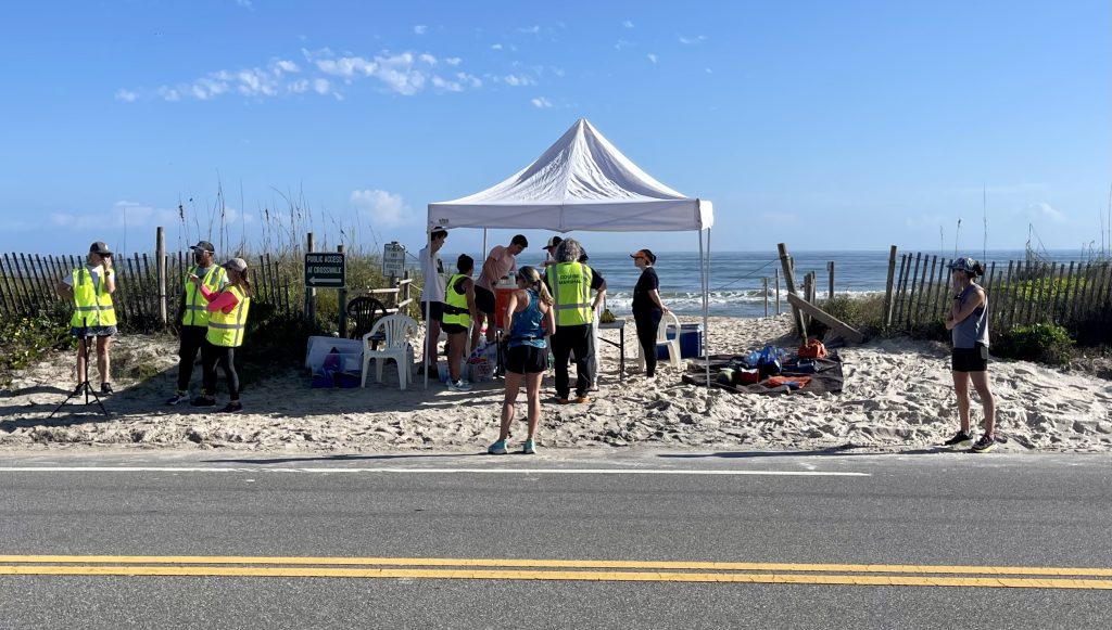 Daytona Delivered - a group of people in hi visibility vests at an aid station on a beach