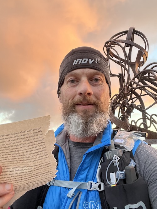 Running into Trouble: Garry taking a selfie holding a page from a book with a wire sculpture behind him