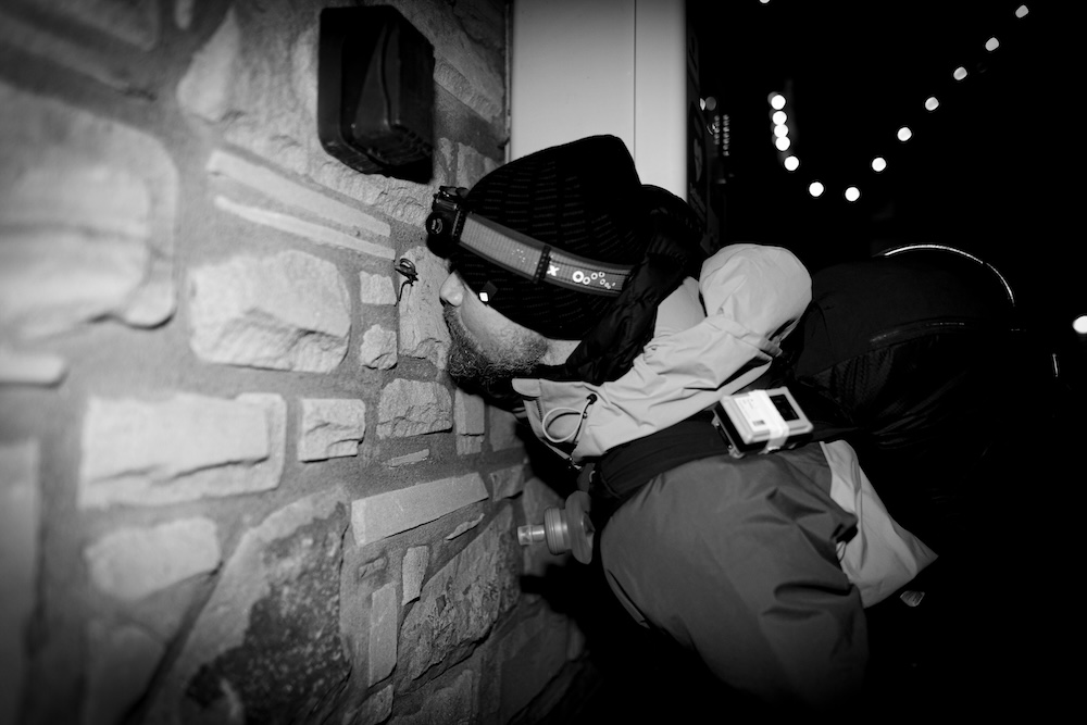 A black and white photo of Sam kissing the wall at the finish of the Winter Spine Race 2024