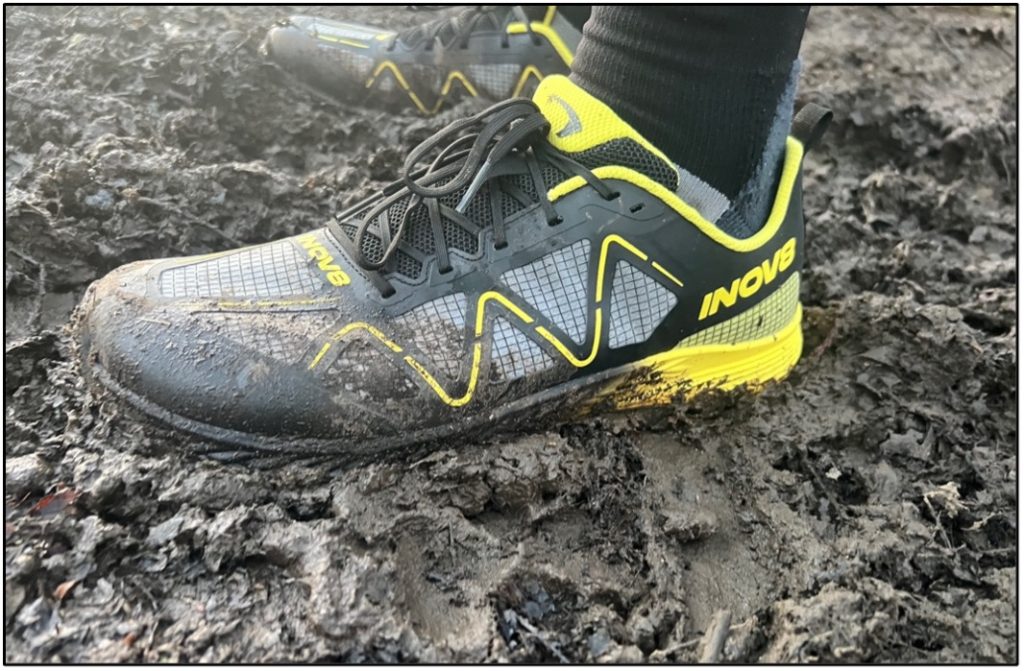 inov8 MUDTALON SPEED A pair of grey and yellow trail running shoes in deep mud