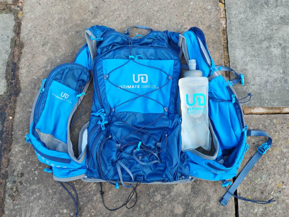 Ultimate Direction Adventure Vest Vesta 6.0 RunUltra Review A blue vest lying on the ground made of paving slabs