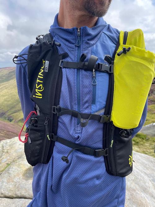 Instinct XX20-24 Trail Running Vest.  A man in a blue top modelling the black and yellow vest from the front with three straps across his chest to hold it in place