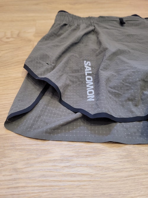 Salomon Sense Aero 3" Shorts Review a pair of brown shorts laid out on a wooden table so that you can see the detail of the fabric and the black edging