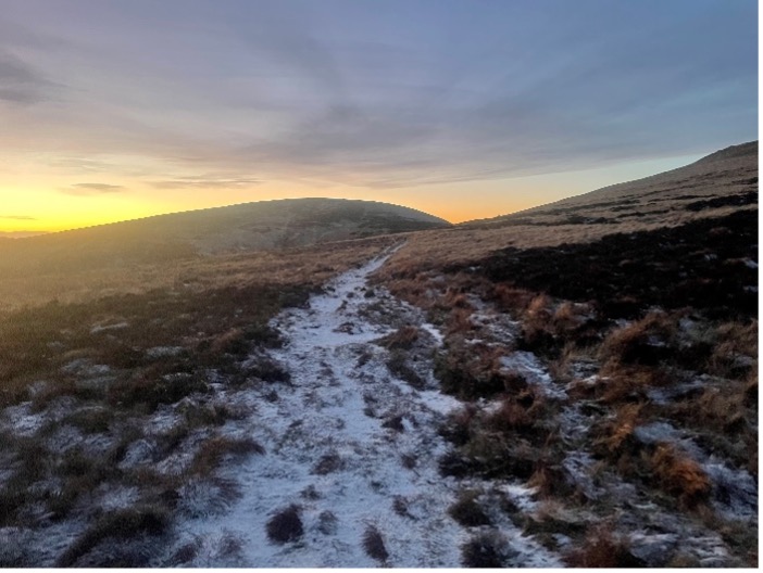 A snowy path stretches ahead across a frozen moorland